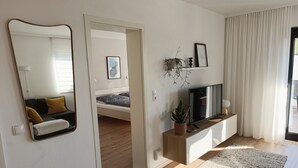 Una sala de estar moderna con cama, televisor y planta.