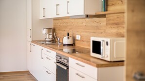 Een keuken met witte kastjes, een houten aanrecht, een koffiezetapparaat, een broodrooster en een magnetron.