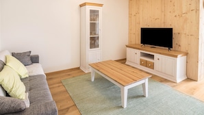 Een woonkamer met een bank, een salontafel, een kast en een televisie.