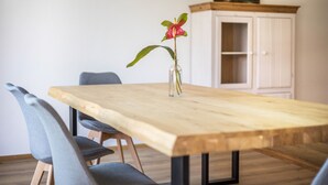 Een eettafel met stoelen, een vaas met een bloem en een kast in een kamer.