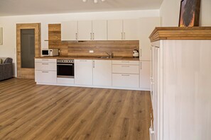 Una cocina moderna con armarios blancos, un microondas, una estufa y un fregadero.