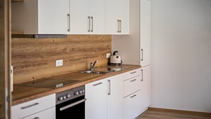 Una cocina moderna con armarios blancos, encimera de madera, horno empotrado y hervidor.