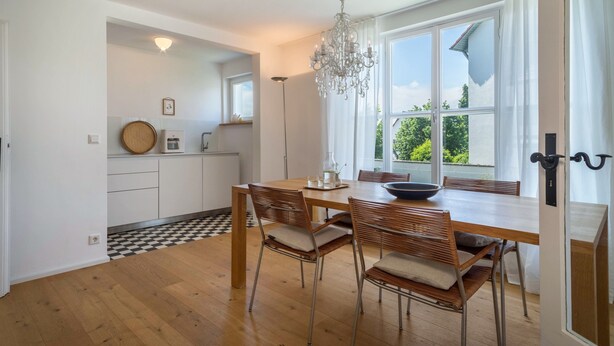 A modern kitchen with white cabinets, a wooden dining table, and a chandelier. - "Holiday cottage Fischbach" close to the Lake with Wi-Fi (Friedrichshafen)