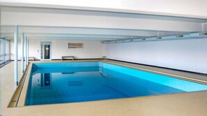 En inomhuspool med klart vatten, en hoppställning och en livräddarstol.