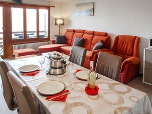 Uma área de refeições com uma mesa posta para dois, um fogão portátil e uma garrafa de vinho.