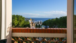 Un balcó amb vista al mar, una ampolla i tres vasos.