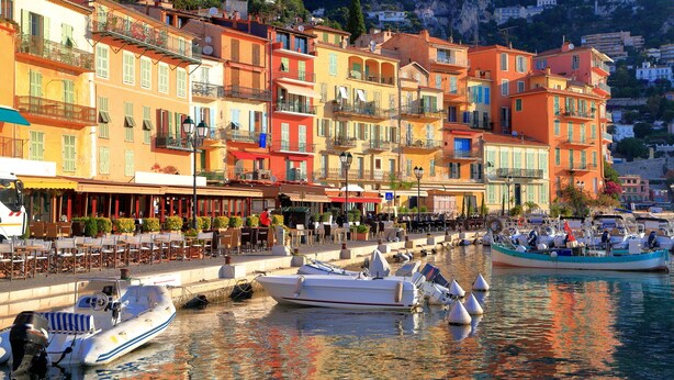 Un passeig marítim amb edificis de colors, una marina amb embarcacions i zones d'esplai a l'aire lliure.