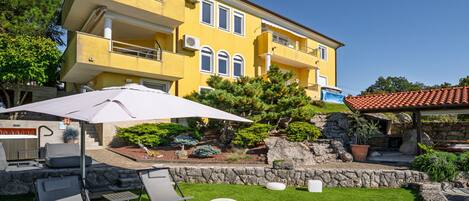 A yellow building with a balcony, outdoor seating, and a fire pit.