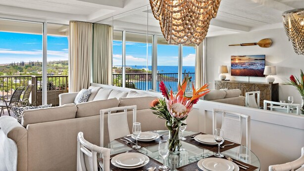 Un vaste espace de vie avec un balcon donnant sur un paysage magnifique, une table à manger pour quatre personnes et un coin salon confortable.