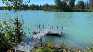 Une jetée s’avançant dans une étendue d’eau calme, entourée d’une végétation luxuriante et d’arbres.