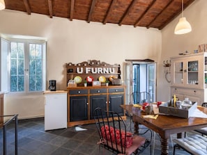 Kitchen area with a refrigerator, dining table, and pendant light.