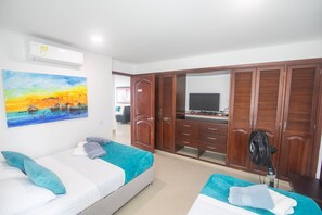 A hotel room with two beds, a large wardrobe, a TV, and a painting on the wall.