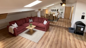 A cozy living room with a red sectional sofa, a wooden coffee table, and a fireplace.