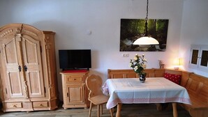 Un comedor con una mesa de madera, sillas, un televisor y un armario.