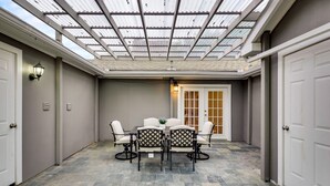Un patio techado con una mesa y sillas, una puerta y una lámpara.