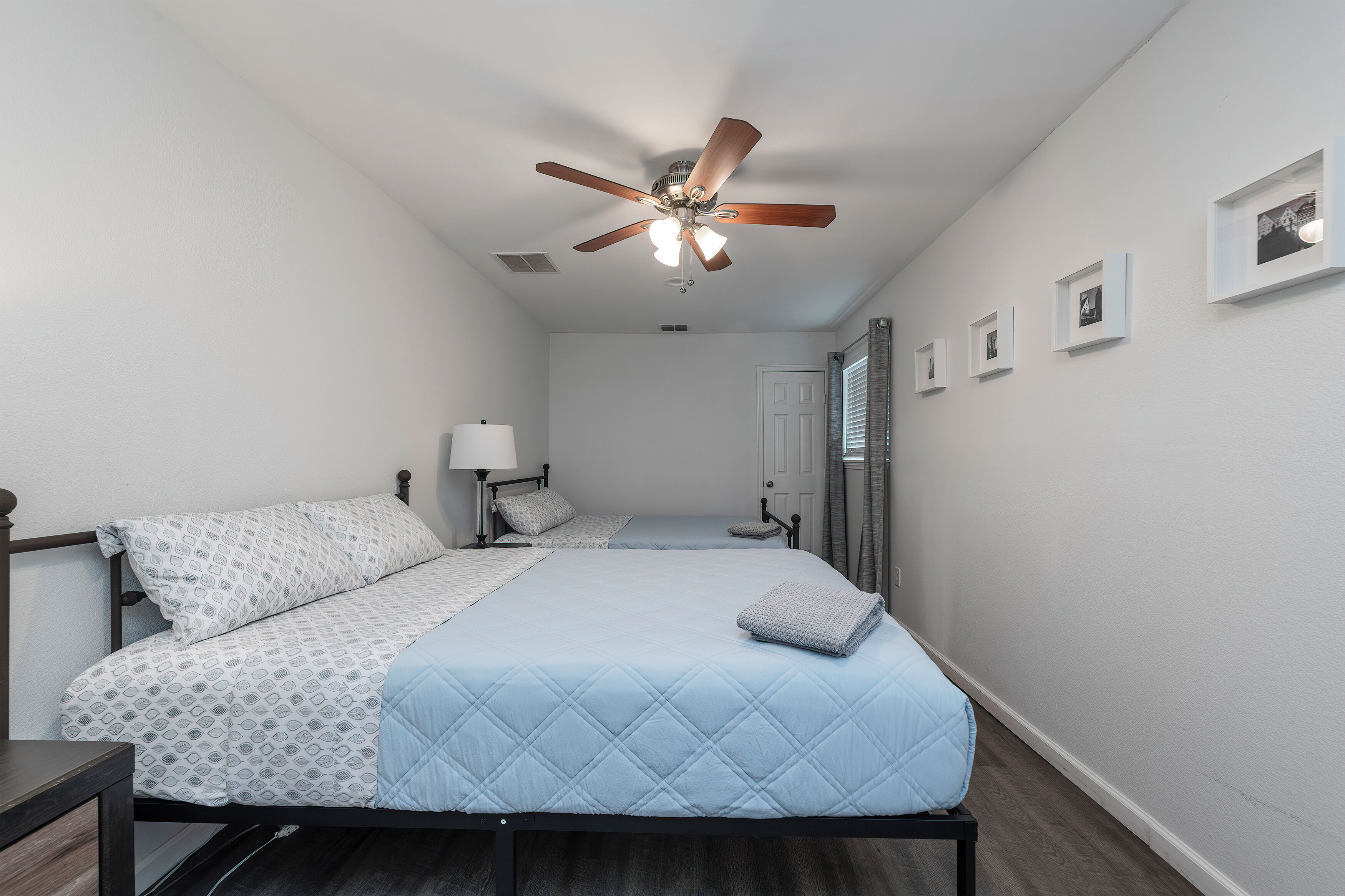 A bedroom with a bed, a nightstand, a ceiling fan, and a door.