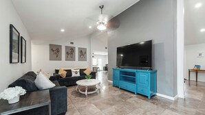 Una sala moderna con un sofá, una mesa de centro y un televisor sobre un mueble azul.