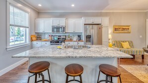 A modern kitchen with a marble island, stainless steel appliances, and a large window.