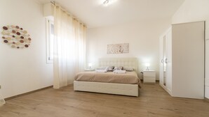 Ein Schlafzimmer mit Bett, Nachttischen, einem Kleiderschrank und einem Wandbild.