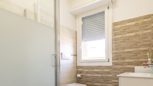 A modern bathroom with a glass shower enclosure, a toilet, and a sink. - Liberty Fiera Bologna (Bologna)