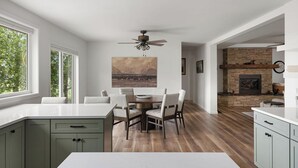 Een moderne keuken met een eethoek, houten vloeren en een open haard.