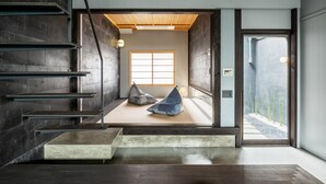 A modern interior with a staircase, a tatami mat room, and a view of a garden. - Souhi Machiya House (Kyoto)