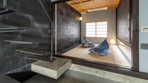 A modern interior with a tatami mat room, a wooden ceiling, and a view through a wooden door. - Souhi Machiya House (Kyoto)