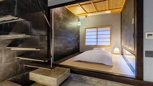 A modern hotel room with a minimalist design, featuring a bed with white bedding, a wooden ceiling, and a large window with a view of the outside. - Souhi Machiya House (Kyoto)
