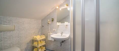 Une salle de bain avec des toilettes, un lavabo et une douche.