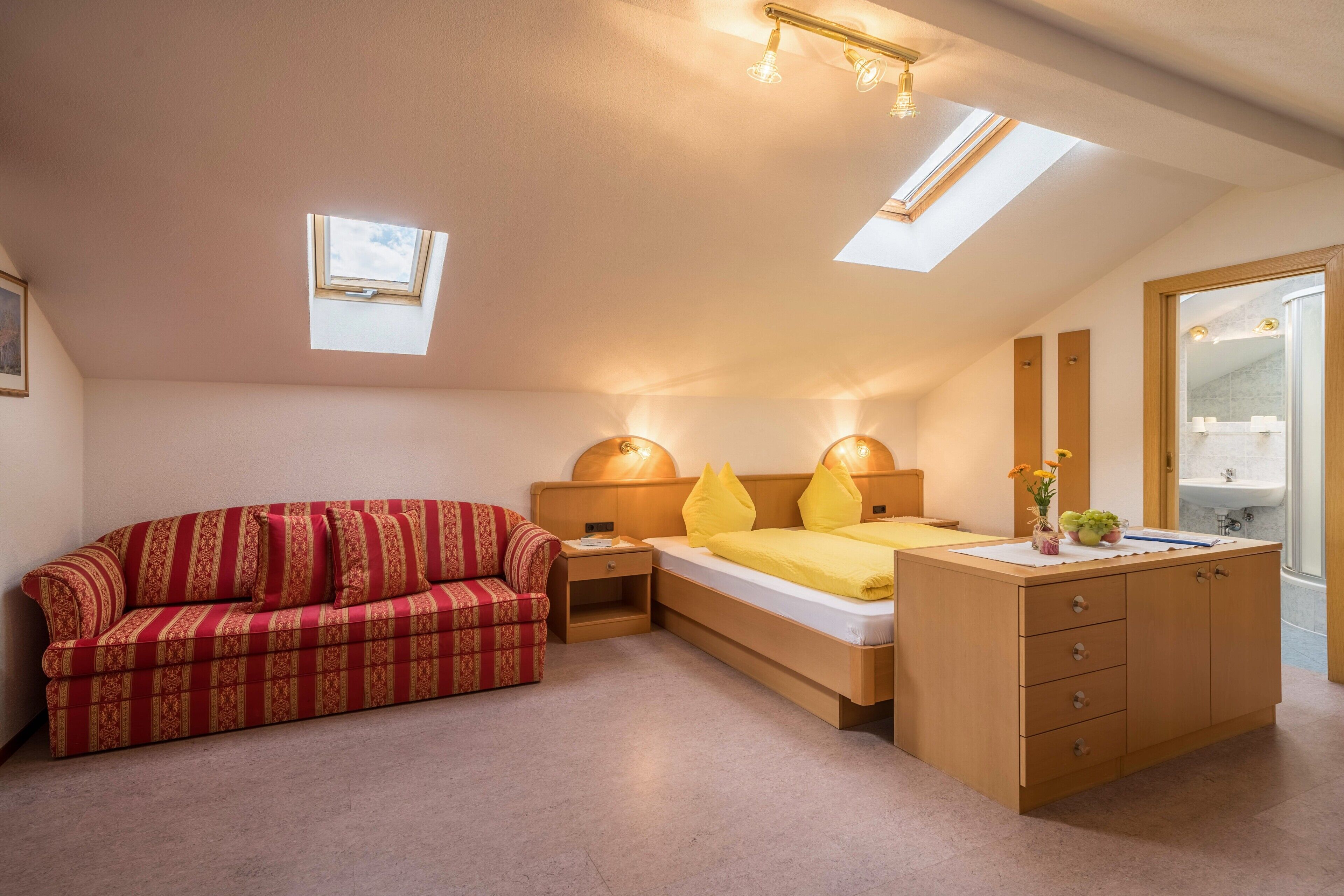 Une chambre à coucher comprenant un lit, un canapé, une coiffeuse et une lucarne.