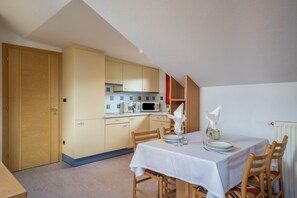 A dining area with a table set for two, a microwave, and a wooden door.