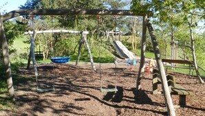 Un parque infantil con columpios, un tobogán y un conjunto de columpios.