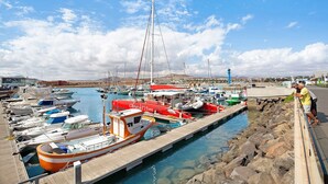 Ein Hafen mit verschiedenen Booten an den Liegen, einer Holzsteganlage und einer felsigen Küstenlinie.