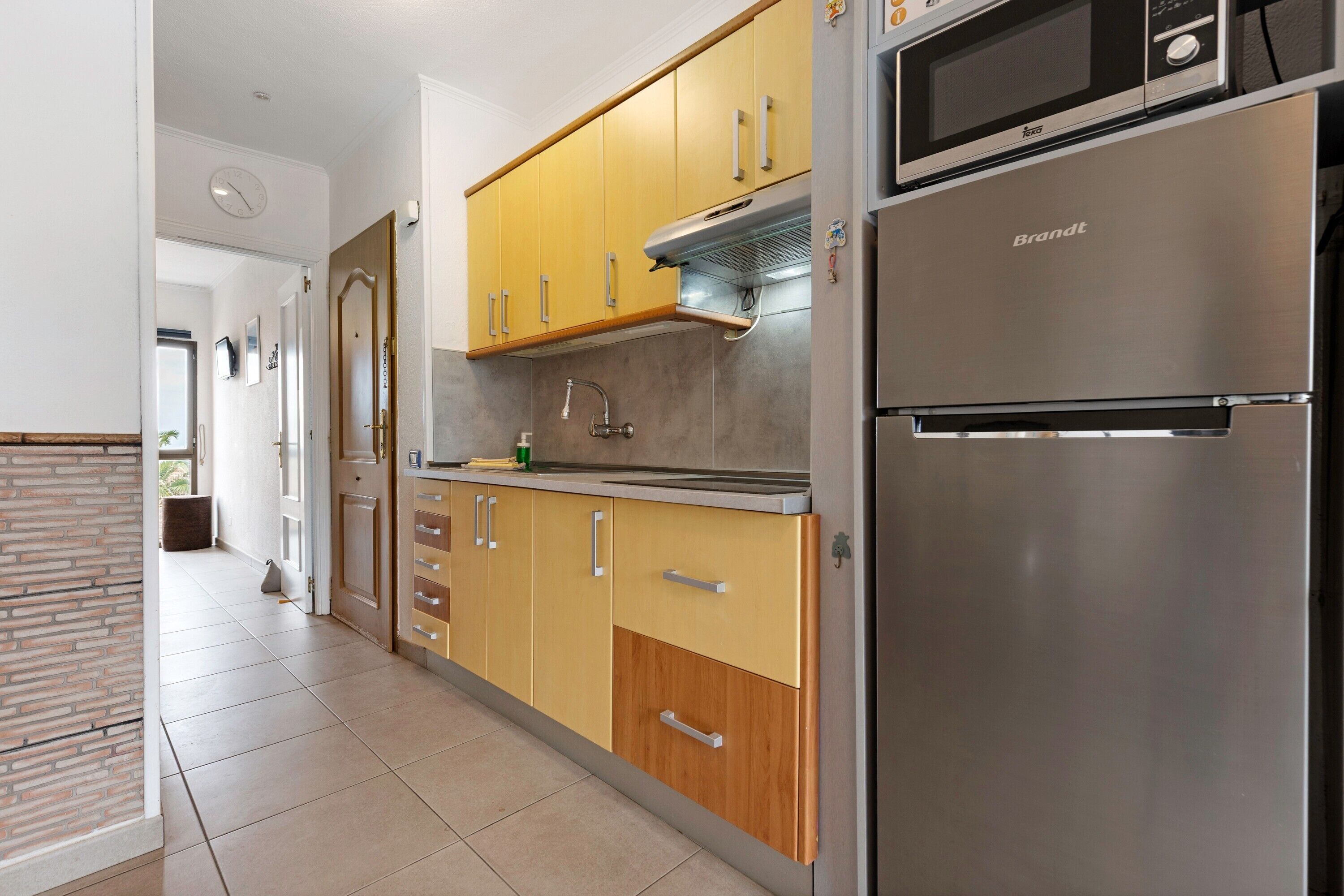 Une cuisine moderne avec des meubles de couleur jaune, un réfrigérateur en acier inoxydable et un four à micro-ondes.