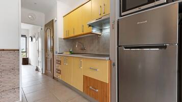 Une cuisine moderne avec des meubles de couleur jaune, un réfrigérateur en acier inoxydable et un four à micro-ondes.