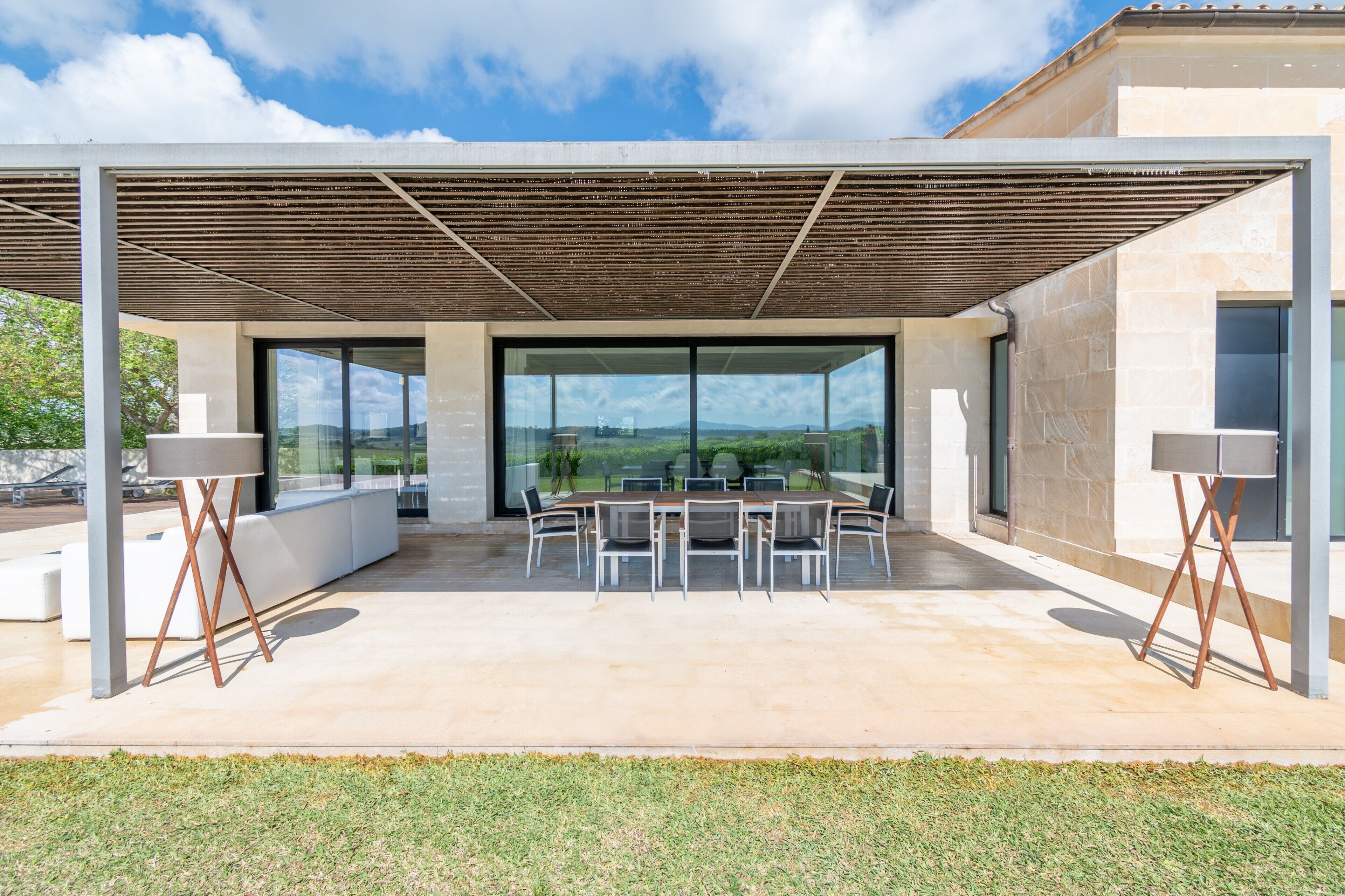 Un patio exterior con mesa y sillas, una pérgola y vistas del paisaje.