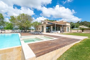A modern house with a swimming pool, outdoor seating, and a patio area.