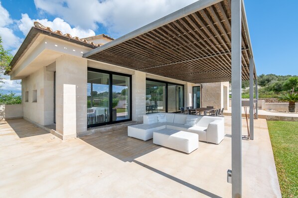 A modern house with a covered patio, large windows, and a sectional sofa.