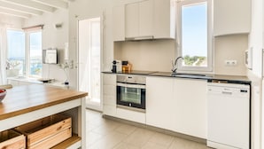 Una cocina moderna con armarios blancos, encimera de madera, horno, lavavajillas y ventana con vistas.