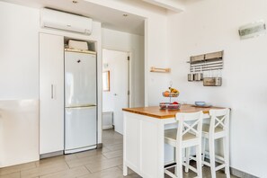 Une cuisine avec un réfrigérateur blanc, un plan de travail en bois et des chaises blanches.