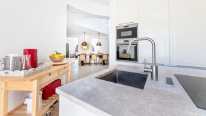 Una cocina moderna con una isla central, horno integrado y electrodomésticos de acero inoxidable.