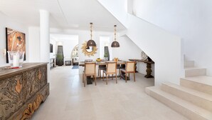 Amplia sala de estar con mesa de comedor, sillas y una escalera.