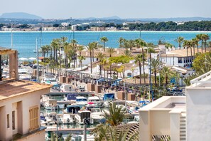 A marina with boats docked, surrounded by buildings and palm trees. - Apartment Casa Rewa Close to the Beach with Sea View, Wi-Fi & Terrace (Puerto de Alcudia)