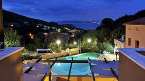 A pool area with a view of a coastal town at dusk.