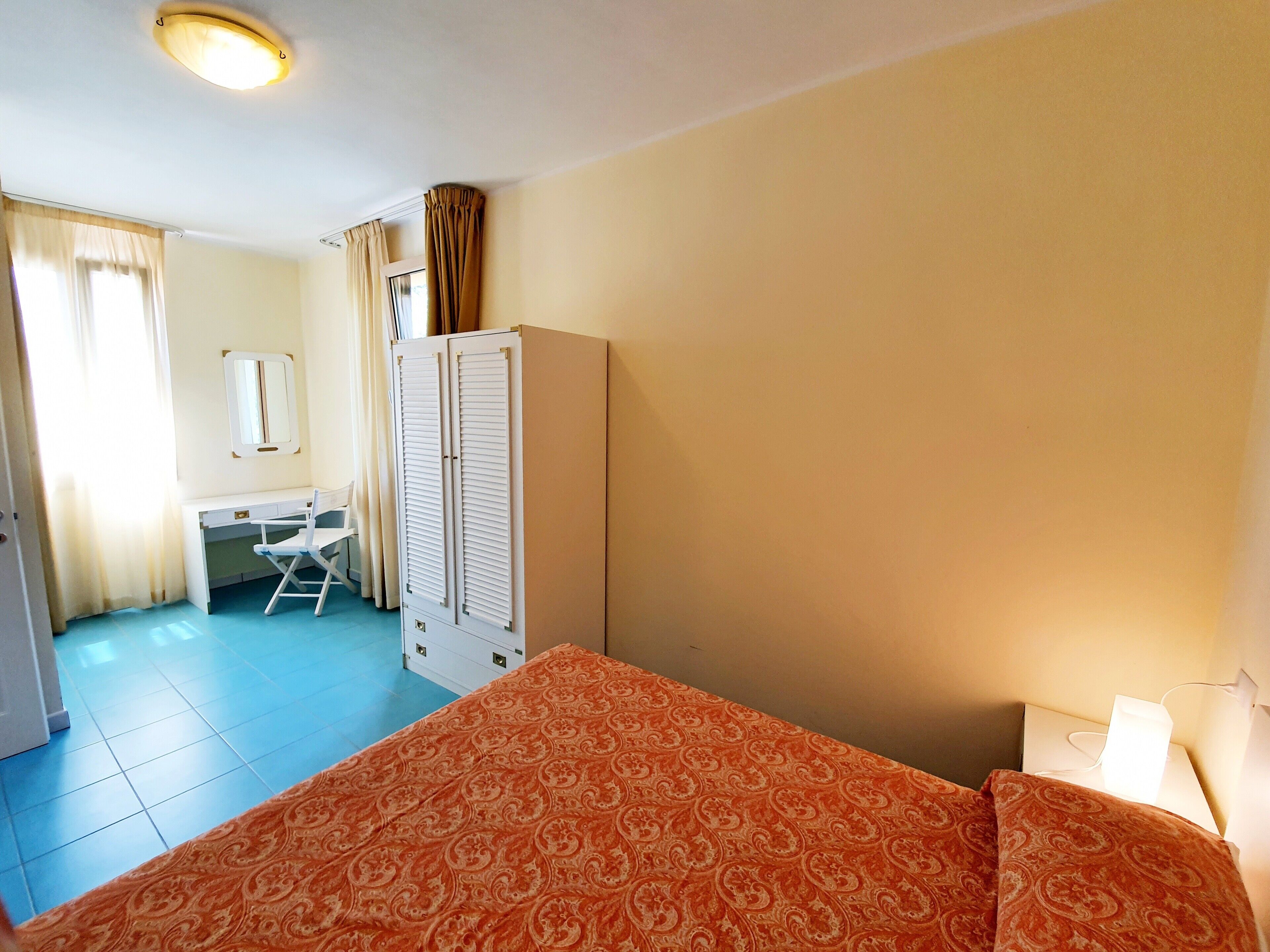 A room with a bed, a desk, a chair, and a wardrobe.