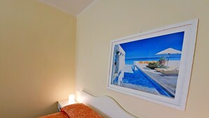 A hotel room with a bed, a nightstand, a wall-mounted painting, and a bedside lamp.