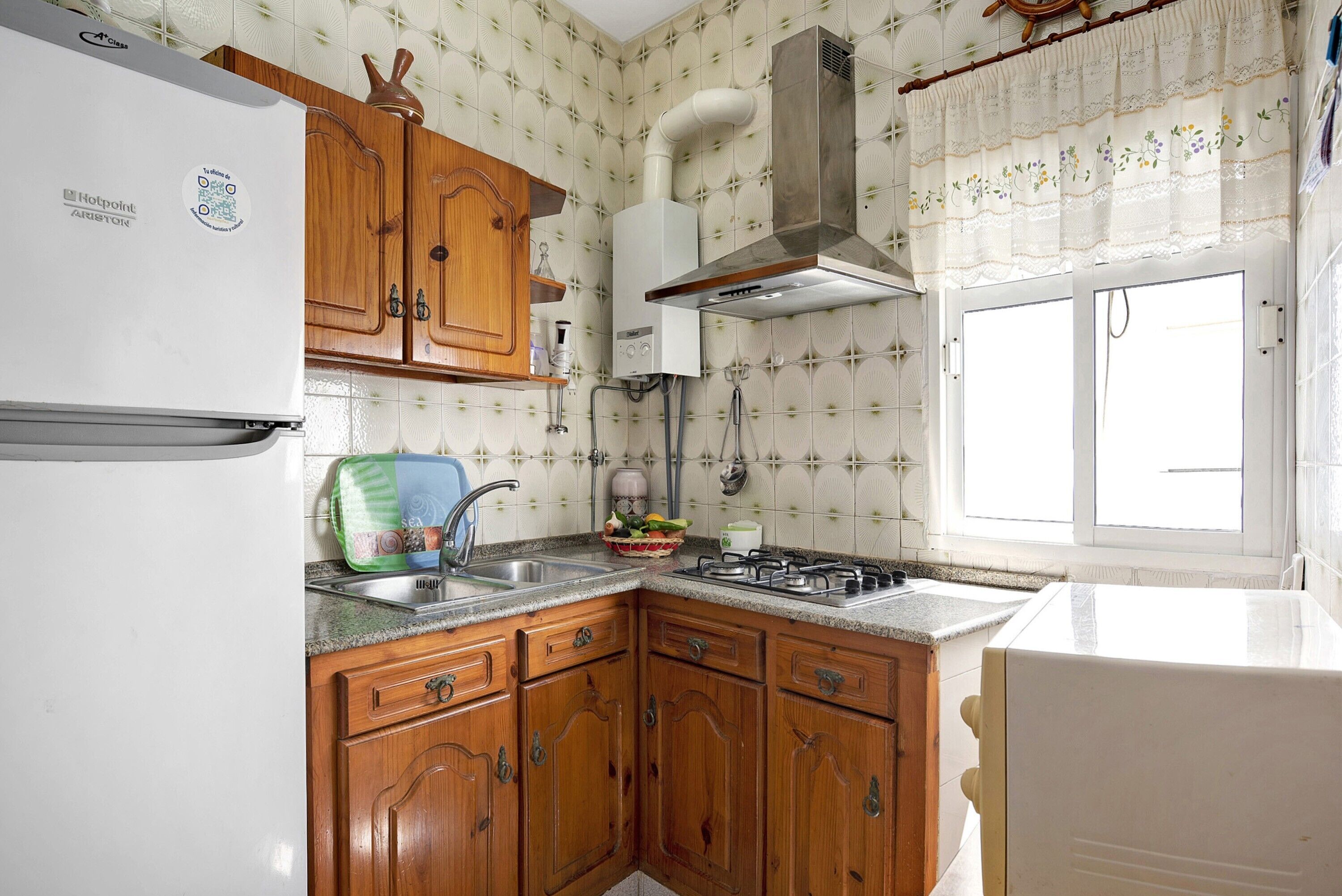 A kitchen with wooden cabinets, a white refrigerator, a gas stove, and a window with a view.