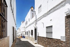Une rue étroite bordée de bâtiments blancs, un lampadaire et une porte bleue.