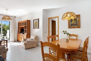 A spacious living area with a wooden dining table, a sofa, and a cabinet.