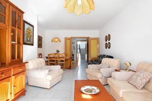 A living room with two sofas, a wooden cabinet, and a dining area with chairs and a table.